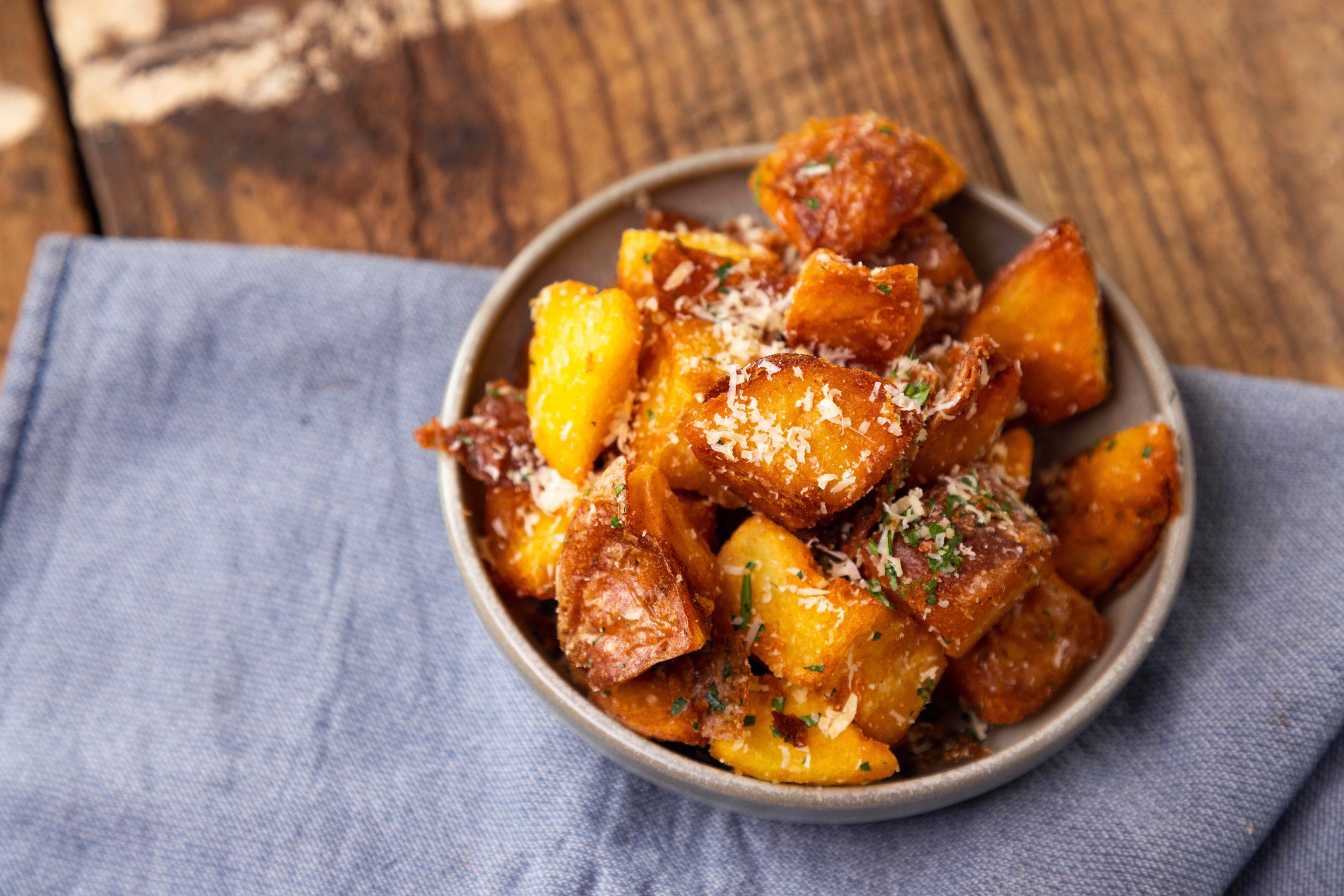 wagyu tallow potatoes with perfectly crispy outside and soft, fluffy potato inside. sprinkled with shaved parmesan and herbs.