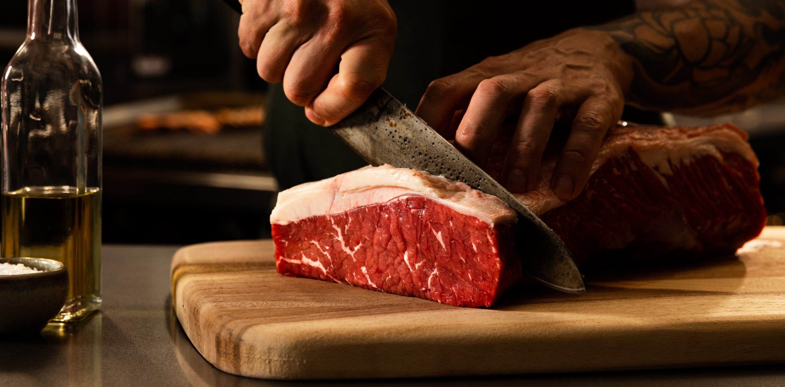 Chef cutting premium quality beef ctriploin into portion cut steak