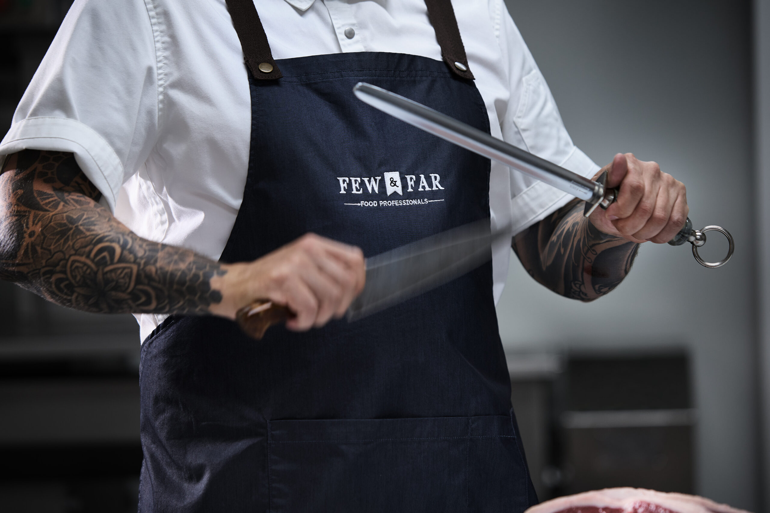 Few and Far Food Professionals Chef sharpening knife to cut premium meat